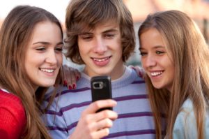 Group of teenager boys and girls looking on mobile phone